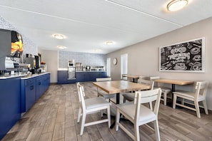 Una cucina moderna con mobili blu, un'isola centrale e un'area pranzo con sedie bianche e un tavolo in legno.