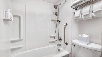 A white bathroom with a bathtub, a shower, and a toilet. There are white towels and a tissue box on the toilet.