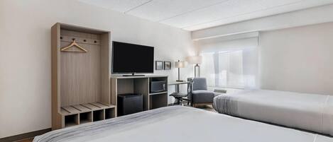 Ett hotellrum med en säng, en tv, ett skrivbord med en stol, en garderob och ett fönster.