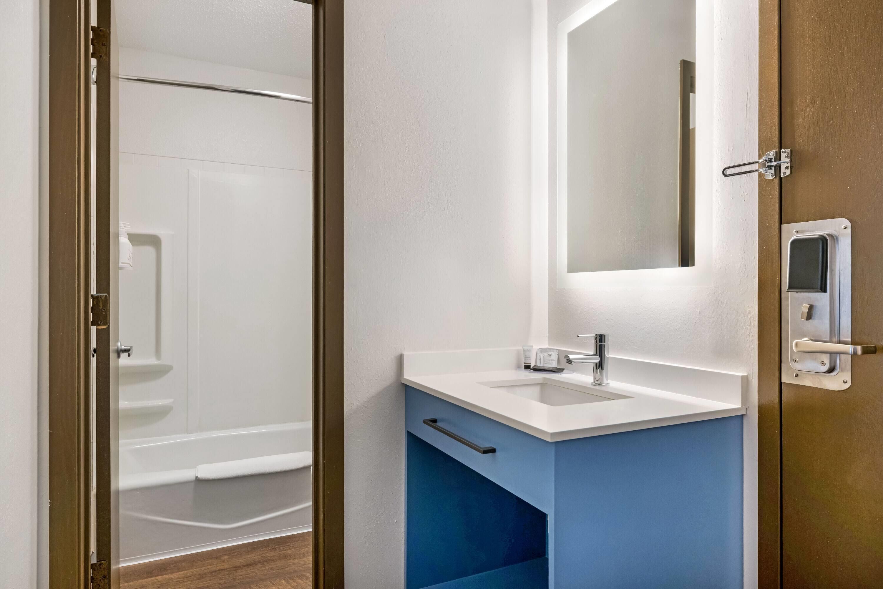 A bathroom with a white sink, a mirror, and a shower.