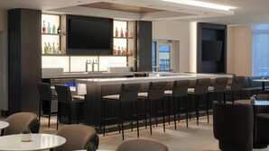 A modern bar area with a long counter, multiple seating options, and a large flat-screen TV. - AC Hotel by Marriott Asheville Biltmore Village (Asheville)