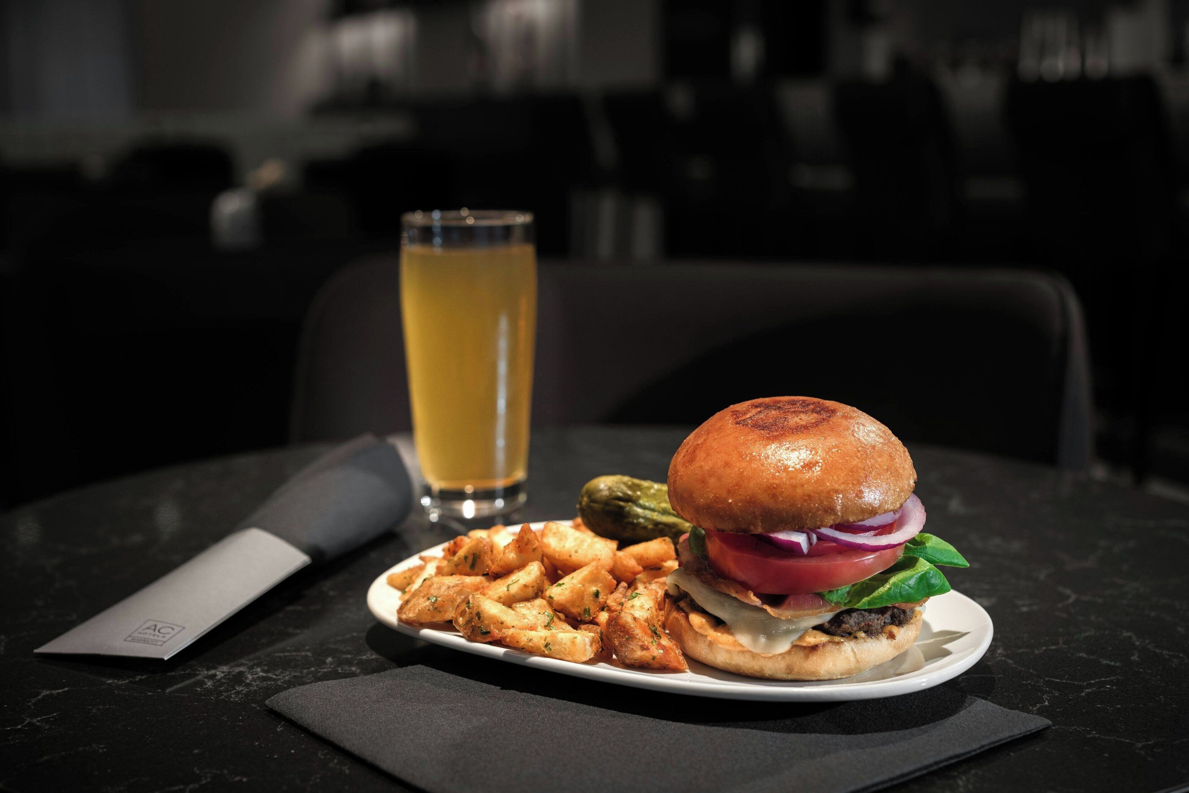 A plate with a burger, fries, and a pickle on a table.