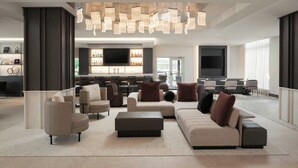 A modern hotel lobby with a large seating area, a bar with a flat-screen TV, and a unique ceiling light fixture. - AC Hotel by Marriott Asheville Biltmore Village (Asheville)