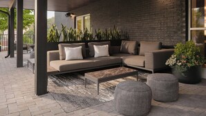 A modern outdoor seating area with a sectional sofa, a coffee table, and potted plants. - AC Hotel by Marriott Asheville Biltmore Village (Asheville)