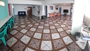 A spacious room with a patterned tile floor, a ceiling fan, and a television on the wall. - Space (Cochabamba)