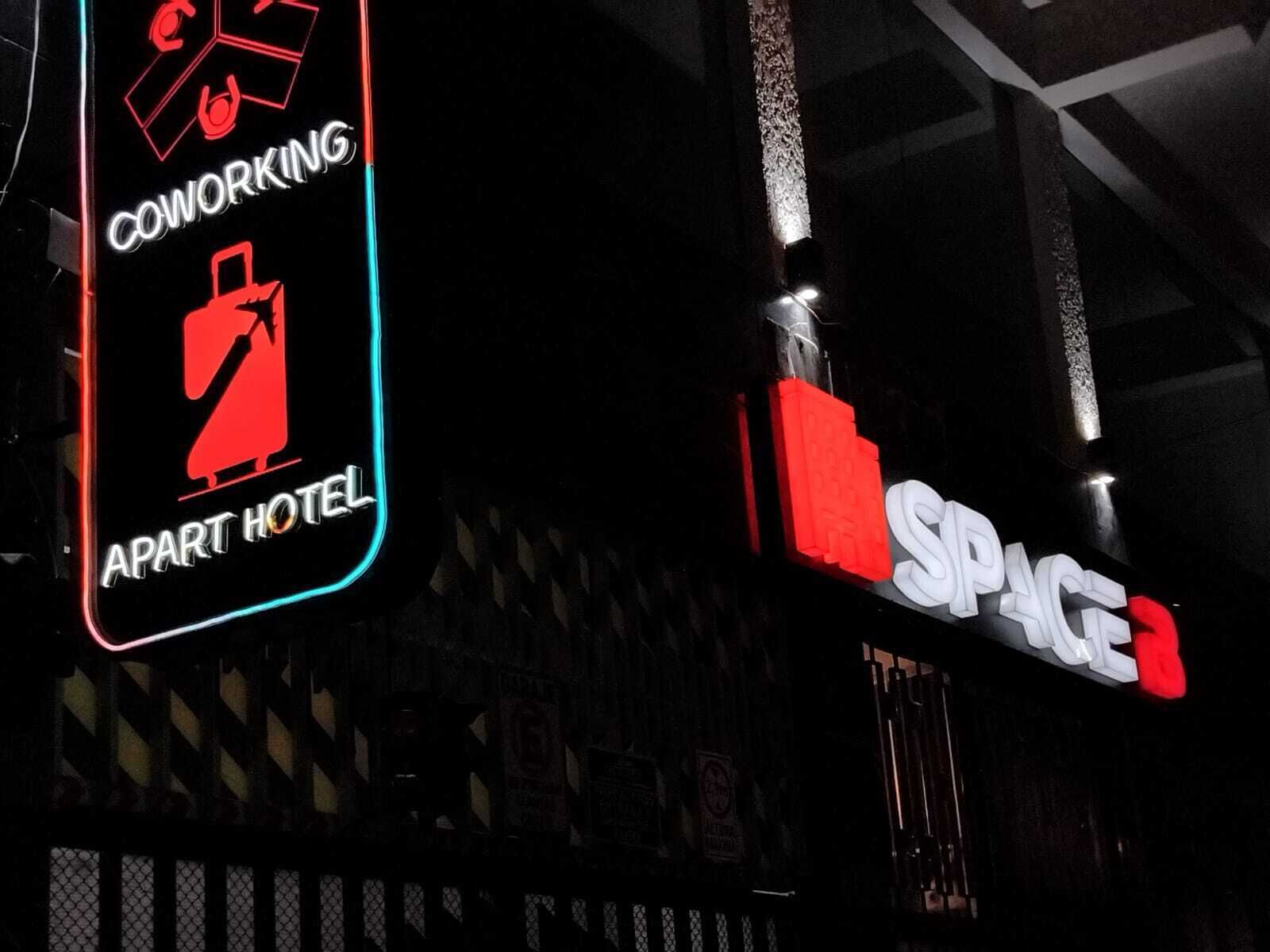 Neon signs for 'Coworking Apart Hotel' and 'Space'.