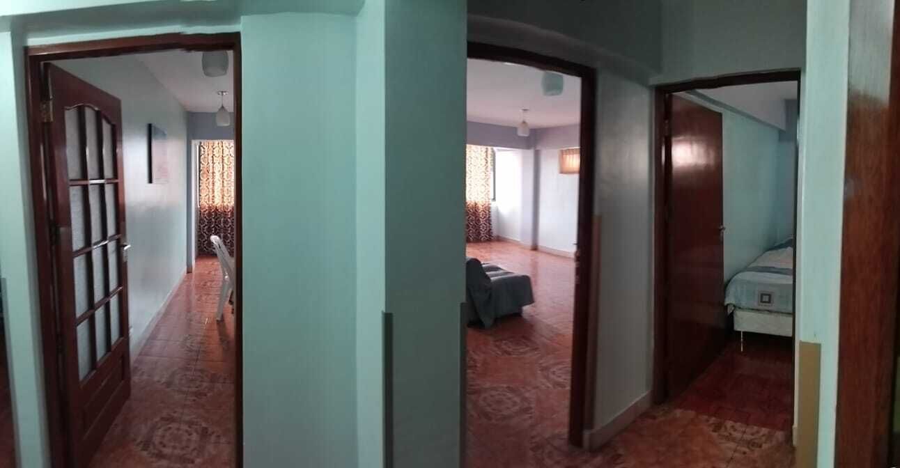 A hallway leading to a room with a bed and a chair.