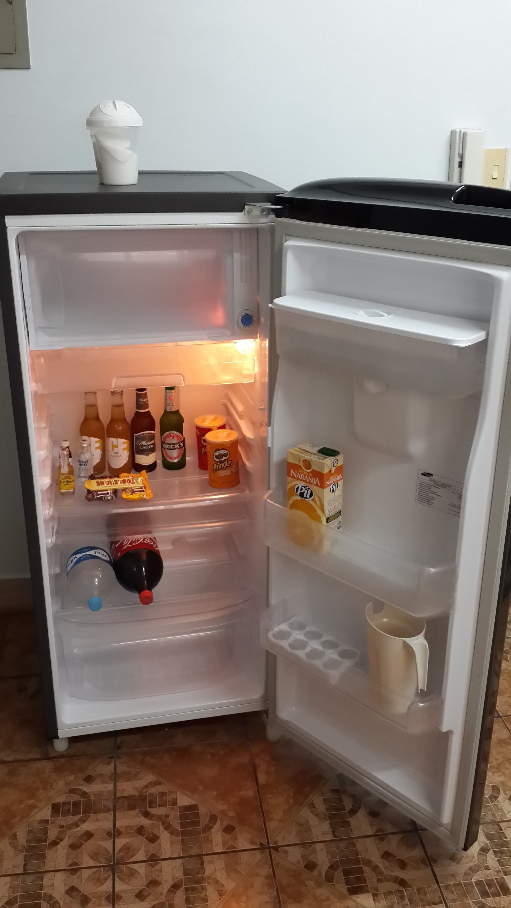Een open koelkast met verschillende drankjes, snacks en een pak sap.
