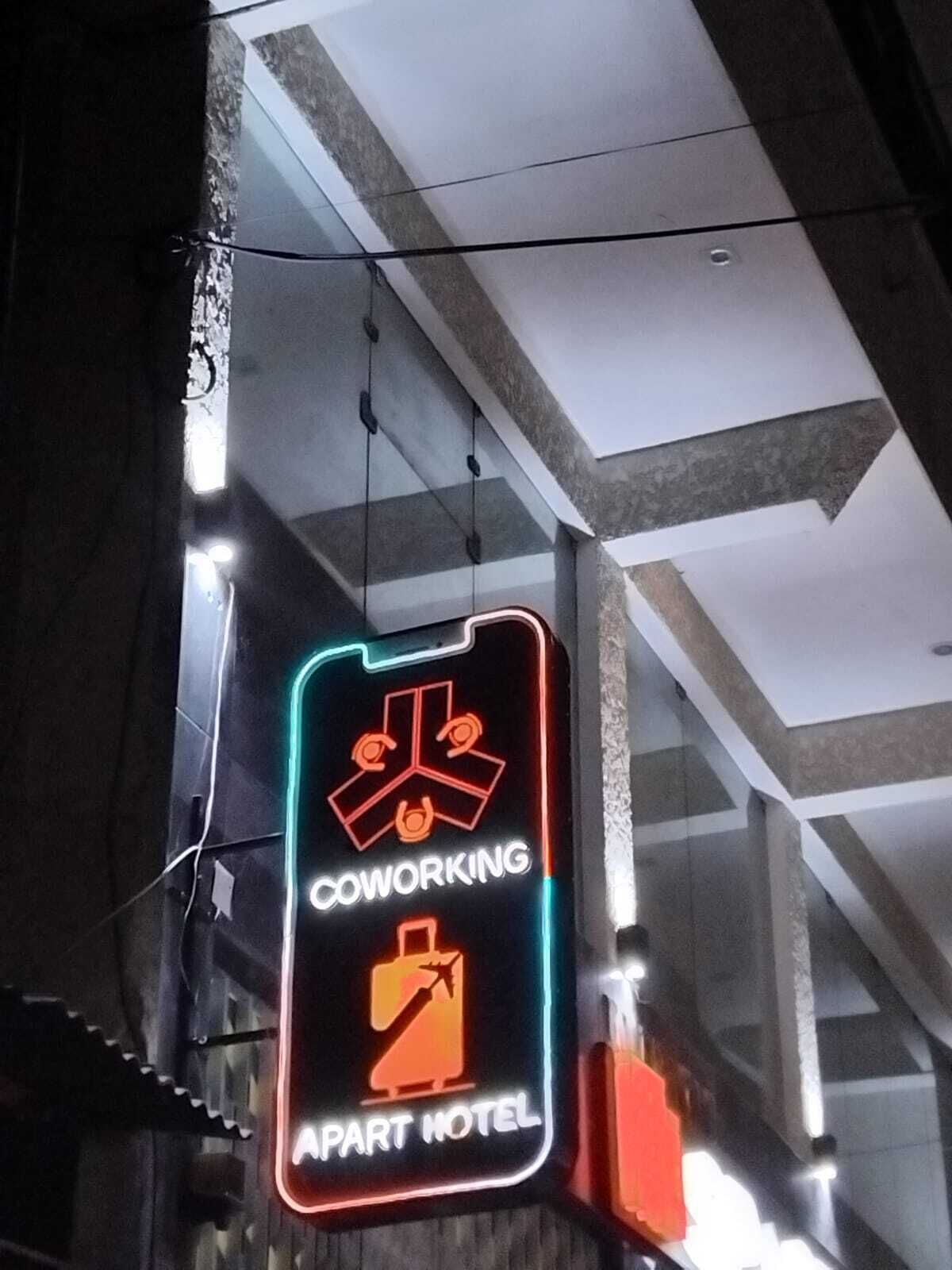 Eine Neonreklame, die einen Coworking Space und ein Apartmenthotel kennzeichnet.