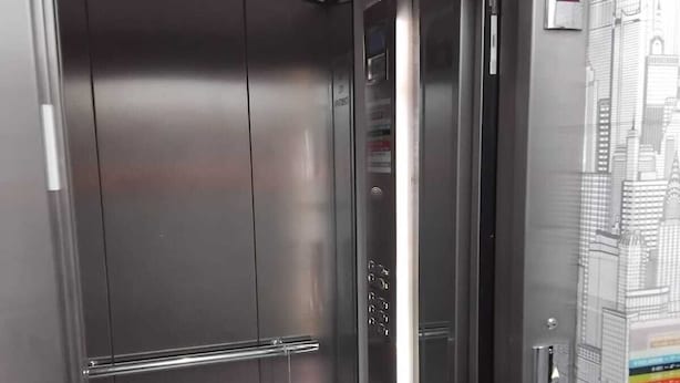 A metallic elevator interior with a control panel and a cityscape mural on the wall. - Space (Cochabamba)