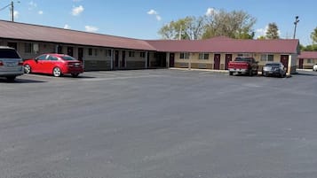 Un motel avec un parking, plusieurs voitures garées et un ciel dégagé.