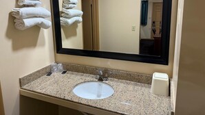 A bathroom with a sink, mirror, and towels on the wall.