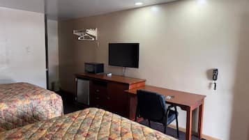 Habitación de hotel con dos camas, un escritorio, una silla, un televisor y un teléfono.