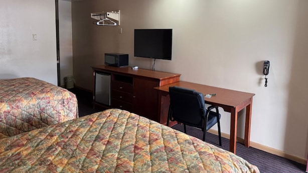Habitación de hotel con dos camas, un escritorio, una silla, un televisor y un teléfono.