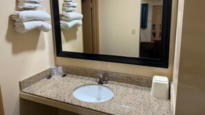 A bathroom with a sink, mirror, and towels on the wall. - Deluxe Inn (Hebron)