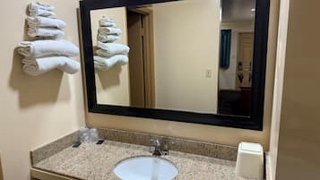 A bathroom with a sink, mirror, and towels on the wall.