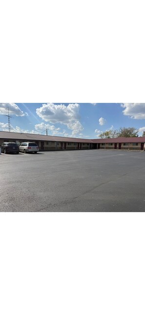 A motel with a large parking lot and a red-roofed building.