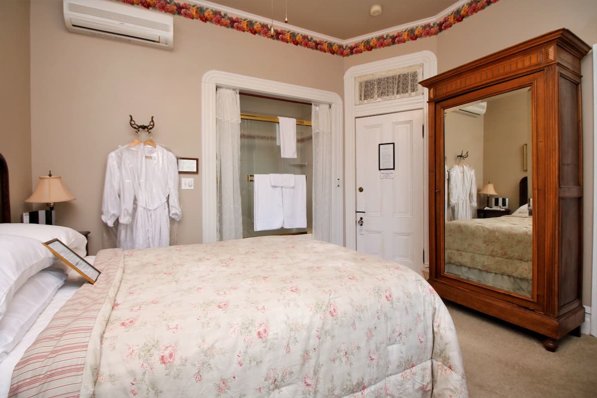 A bedroom with a large bed, a wardrobe, a mirror, and a door leading to a bathroom.