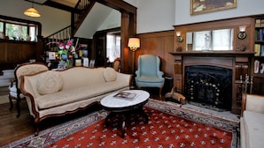 A traditional living room with a sofa, armchair, fireplace, and a patterned rug. - Bradford Place Inn & Gardens (Sonora)