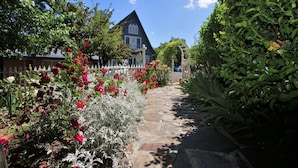 A stone pathway leading to a house with a white picket fence and red flowers. - Bradford Place Inn & Gardens (Sonora)
