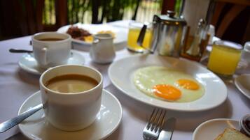 A breakfast setting with a cup of coffee, a plate of eggs, toast, and a pitcher of orange juice.