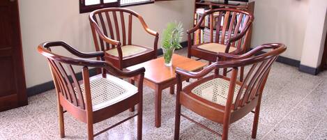 A dining area with a wooden table and four chairs, a small plant on the table, and a fire extinguisher on the wall.