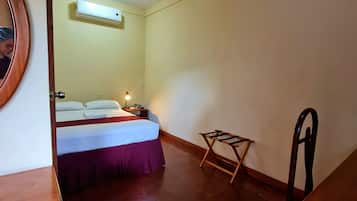 A small, clean room with a bed, a nightstand, a chair, and a small table.
