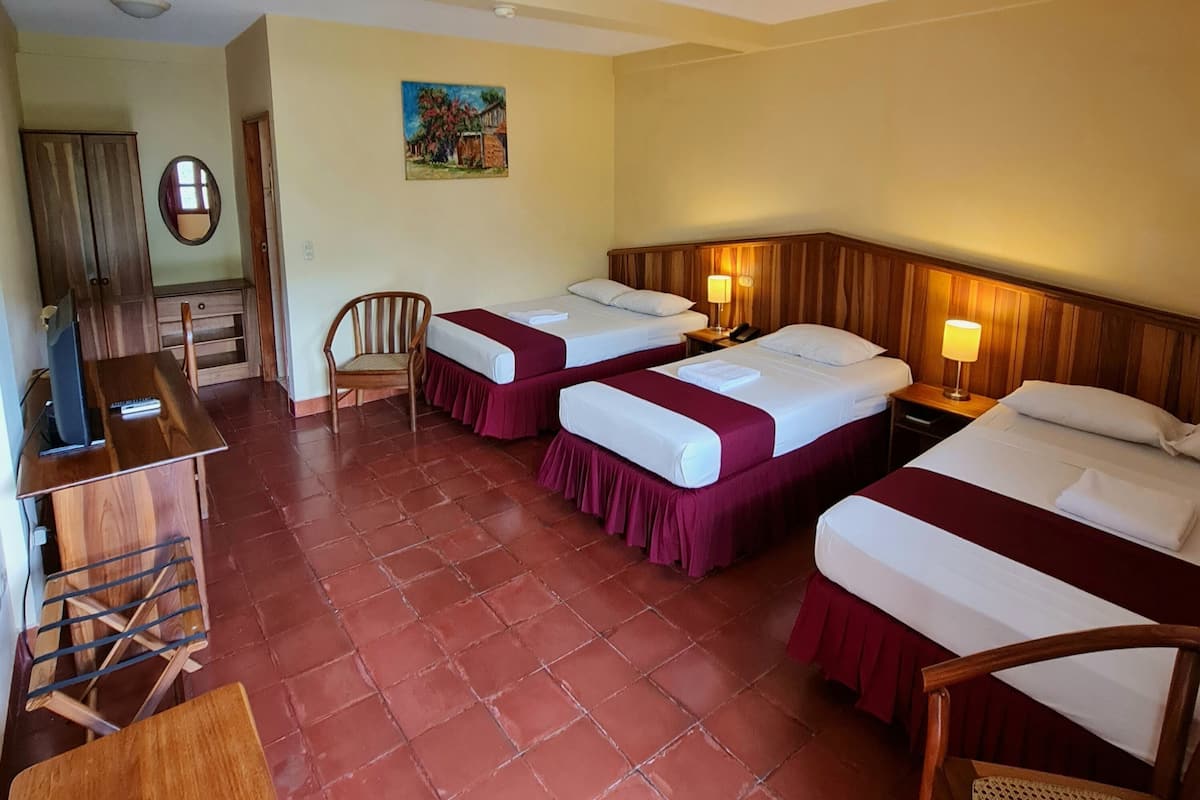A hotel room with two beds, a desk with a computer, a chair, and a painting on the wall.