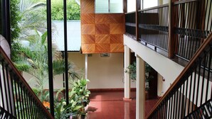 Un intérieur à plusieurs niveaux, doté d’un escalier central, de rampes en bois et d’un sol carrelé.