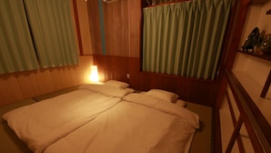 Ein Zimmer mit einem Bett, einem Nachttisch, einer Lampe und einem Fenster mit Vorhängen.