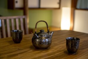 Una mesa de madera rústica con una tetera de metal y dos tazas de cerámica.