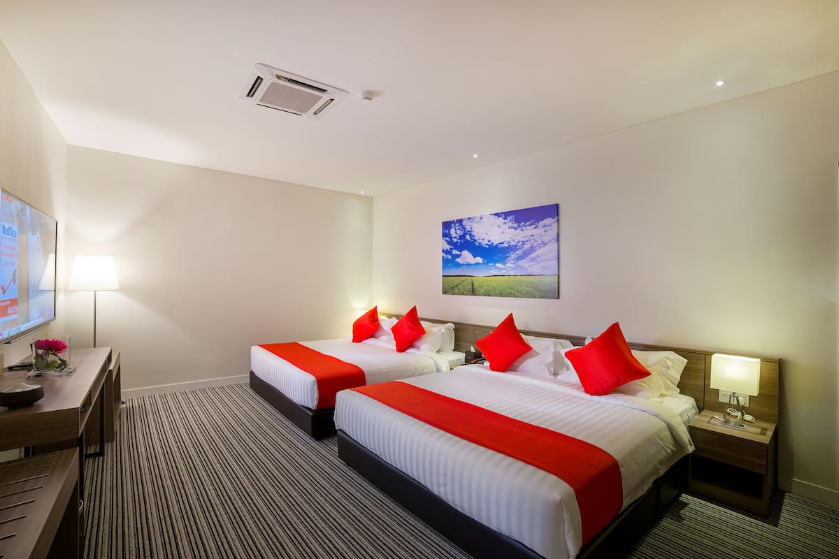 A hotel room with two beds, a desk, a TV, and a painting of a landscape.