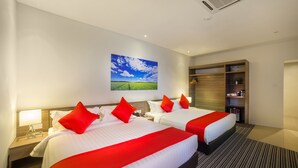 Ein Hotelzimmer mit zwei Betten, rot-weiß gestreifter Bettwäsche, einem großen Fenster mit Blick auf ein grünes Feld und einem Holzschrank.