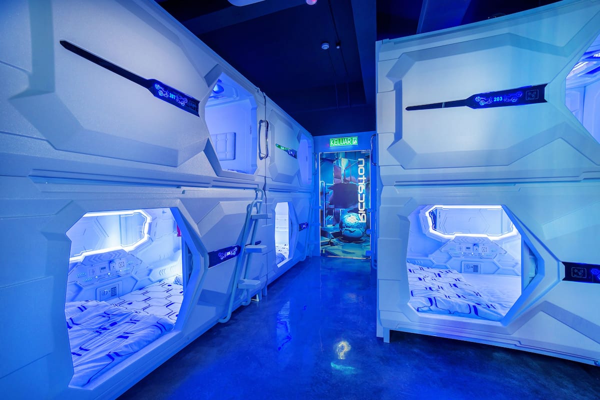 A futuristic room with hexagonal shapes, a bed, and a control panel.