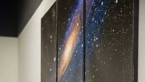 Eine Küche mit einer galaxieartigen Spritzschutzwand, zwei Kübelpflanzen und einer weißen Arbeitsplatte.