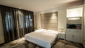 Une chambre d’hôtel avec un grand lit, une table de chevet, une armoire et une fenêtre avec des rideaux.