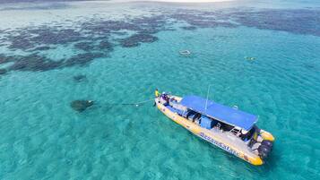 A boat with a blue roof and yellow sides, floating on clear turquoise water.