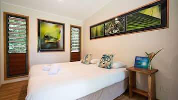 Un dormitorio con una cama grande, una mesita de noche y tres cuadros en la pared.
