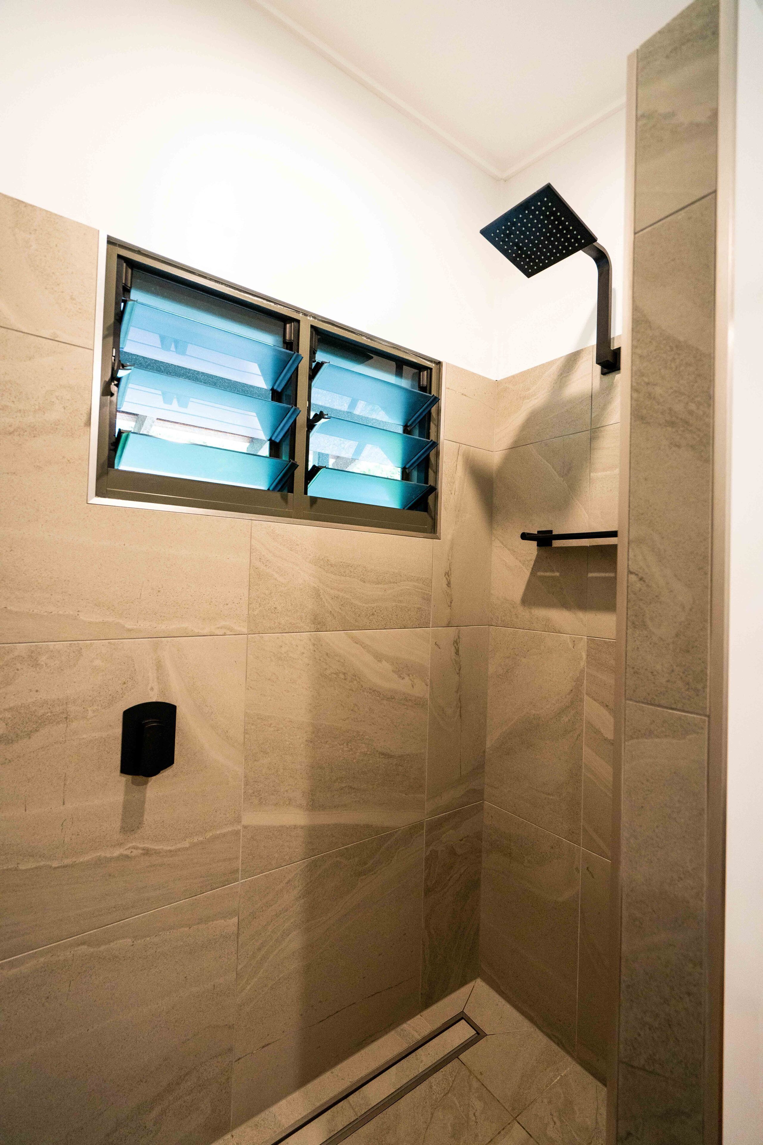 A shower with a built-in window, a towel rack, and a showerhead.