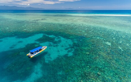 An aerial view of a clear blue sea with a boat on the surface.