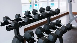 A row of black dumbbells on a rack in a well-lit room with large windows. - Sun Apartment (Phnom Penh)