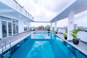 A rooftop swimming pool with glass railings and potted plants, surrounded by a white building with large windows. - Sun Apartment (Phnom Penh)