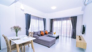 A modern living room with a sofa, dining table, and chairs. - Sun Apartment (Phnom Penh)