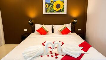 Una cama bien hecha con sábanas blancas, almohadas rojas y un corredor de cama a rayas rojas y blancas. Hay dos lámparas de pared a cada lado de la cama.