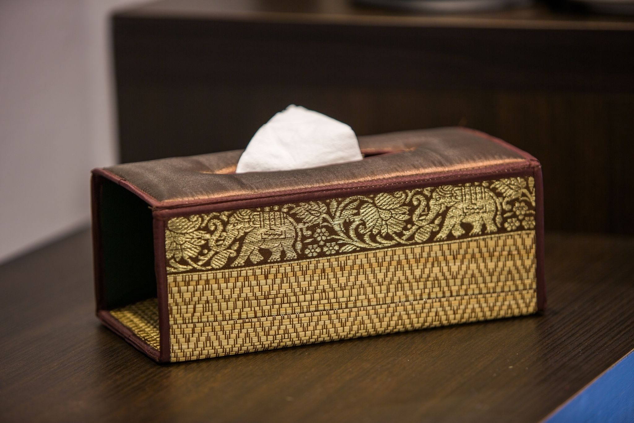 A tissue box with intricate gold patterns on a dark surface.