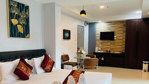Habitación de hotel con una cama grande, un escritorio, una silla, un televisor y un espejo.