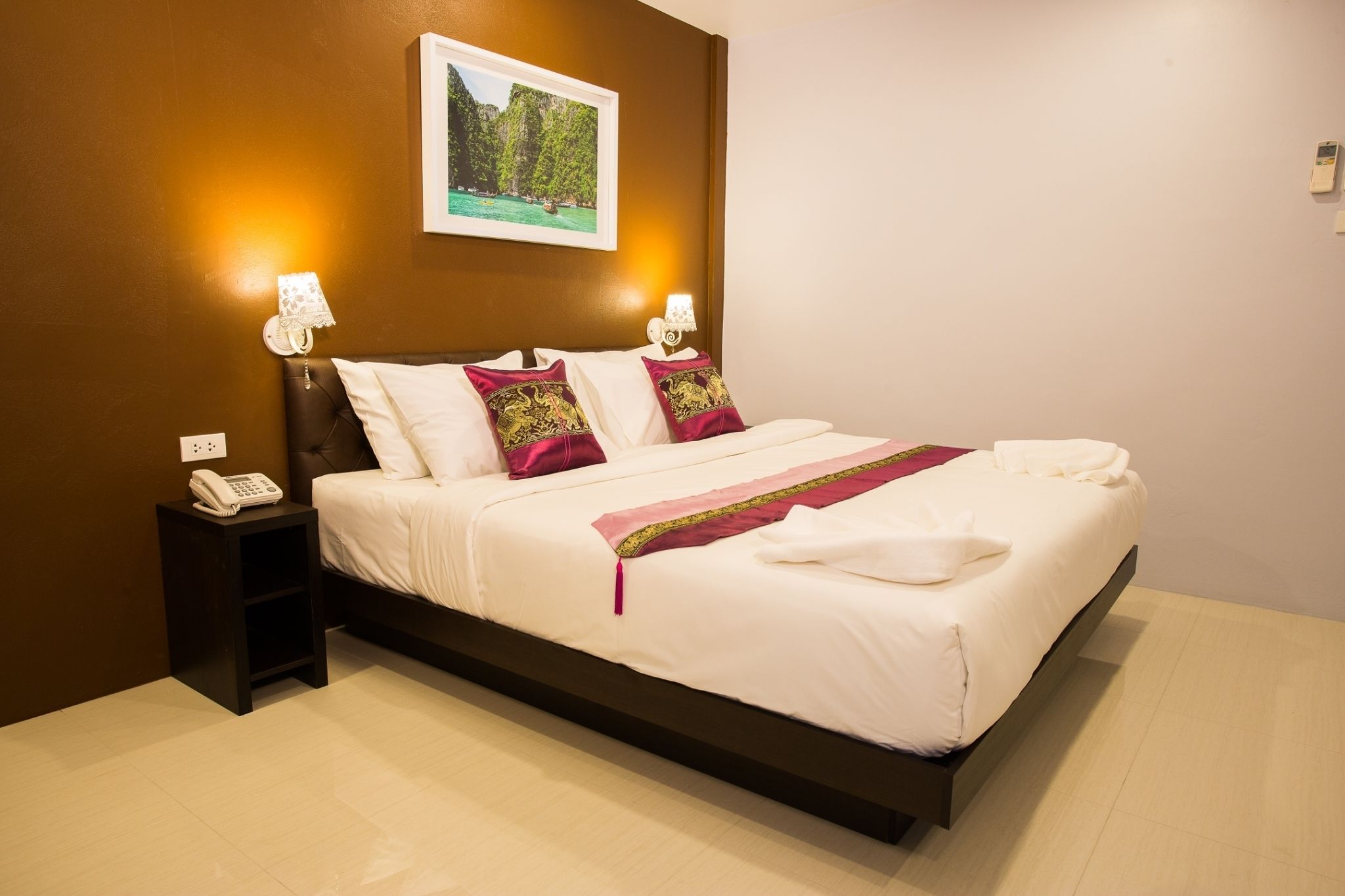 Habitación de hotel con una cama grande, teléfono en la mesita de noche y un cuadro en la pared.