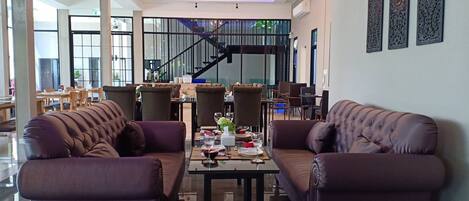 A spacious living area with leather sofas, a central coffee table, and a staircase leading to an upper floor.