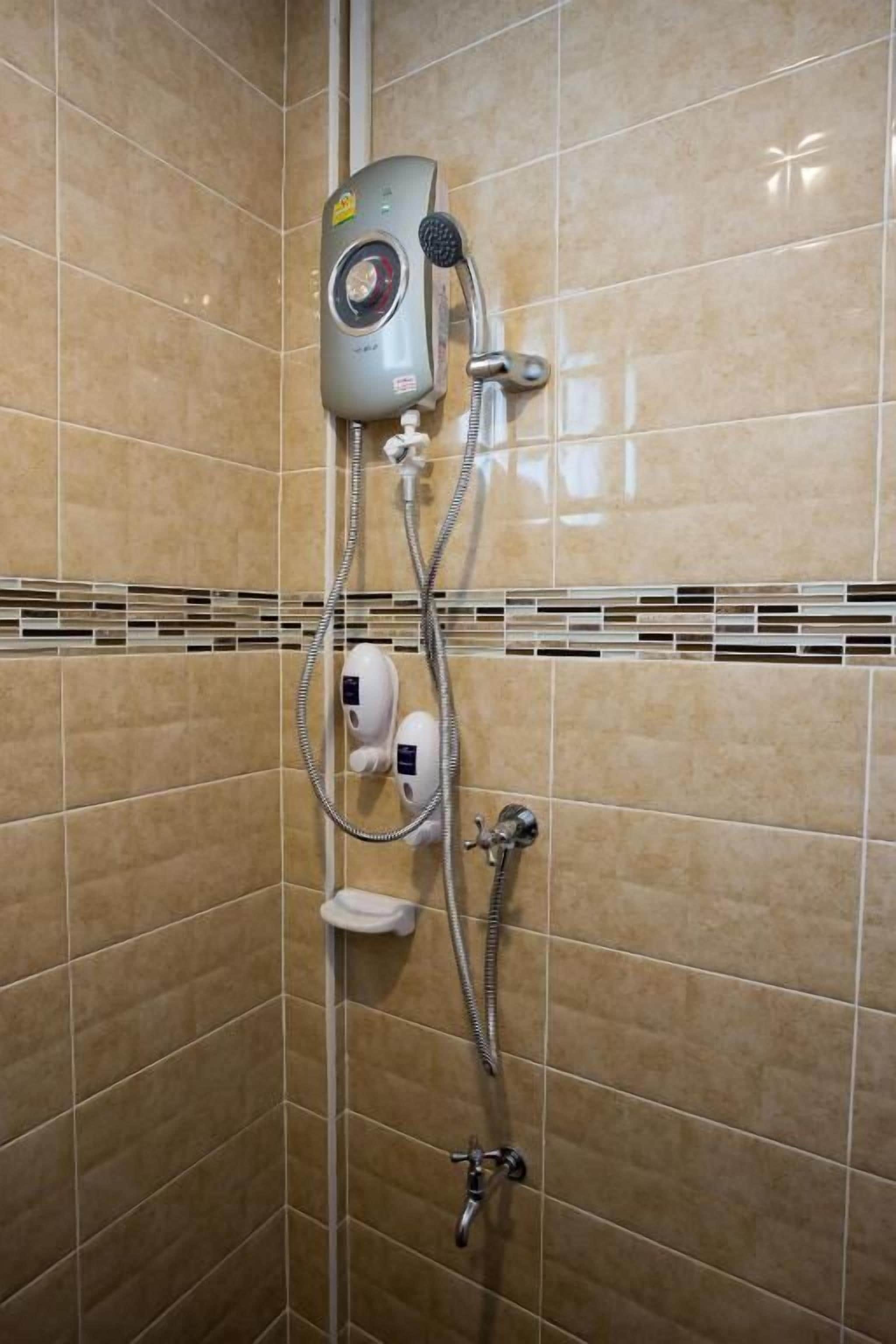 Ducha con cabezal de ducha manual, panel de control en la pared y dispensador de jabón.
