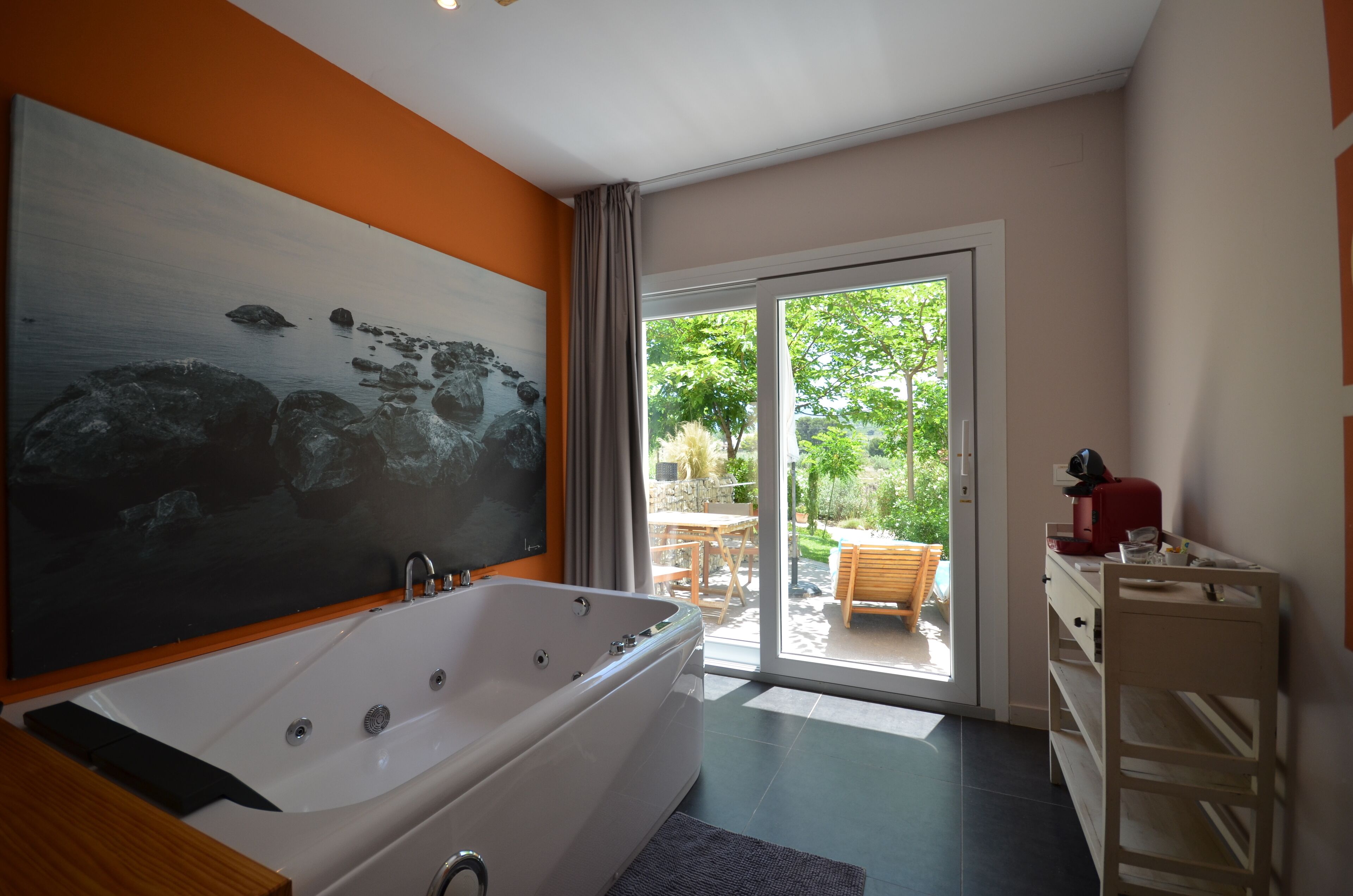 Une salle de bain moderne avec une grande baignoire, un meuble-lavabo en bois et une porte coulissante en verre donnant sur un patio.
